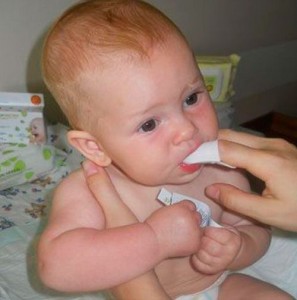 Новорожденному чистят ротик от молочницы