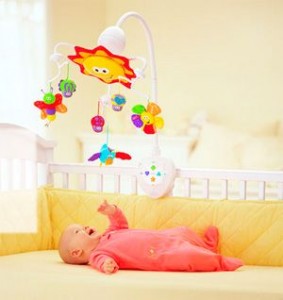 Малыш лежит на спине в кроватке и смотрит на яркие игрушки