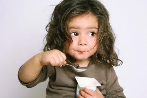 Девочка ест ложкой йогурт