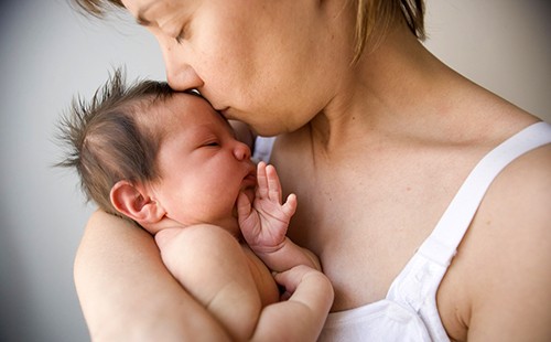 Мама со всей нежностью целует новорождённого
