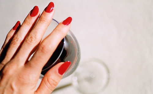 Рука с ярко-красными ногтями прикрывает бокал, потому что умная девушка больше не хочет вина