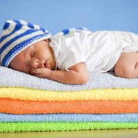 Спящий ребёнок на стопке разноцветных полотенец