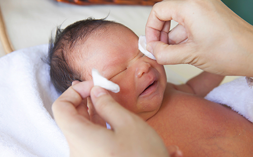Новорожденному младенцу протирают глазки ватными дисками