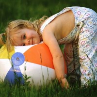 Маленькая девочка лежит на надувном мяче