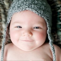 Младенец в вязаной шапочке улыбается