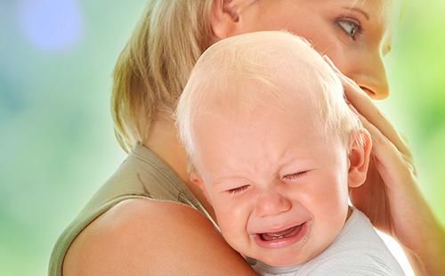 Плачущий малыш на руках у мамы
