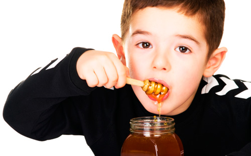 Мальчик ест мед из банки