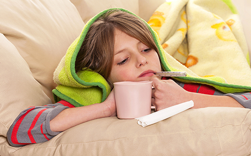 Девочка с температурой кутается в уютное одеяло и пьёт чай