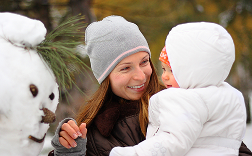 Радостные мама с малышом любуются снеговиком