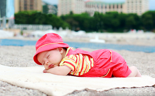 Малышка в розовом спит на пляже