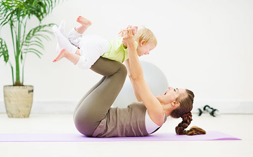 Молодая женщина делает упражнения с малышом