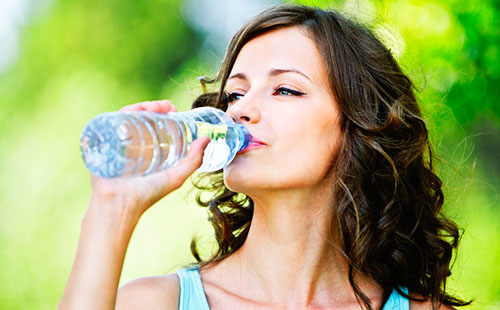 Молодая женщина пьет чистую воду