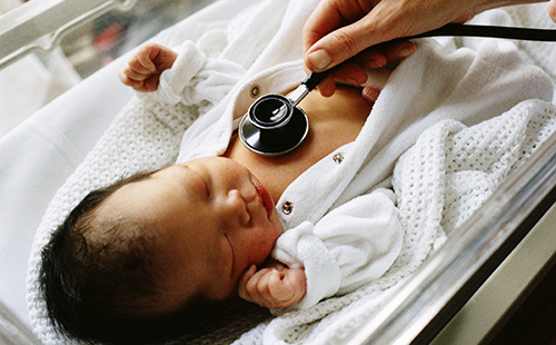 Новорожденного ребёнка прослушивают стетоскопом