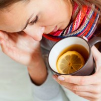 Простуженная женщина пьёт чай с лимоном