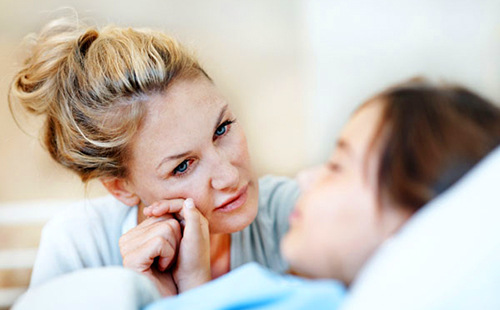Полная тревоги мама сидит у постели заболевшей дочки