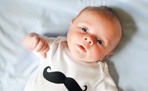 Удивлённый младенец в фуфайке с нарисованными мусташами