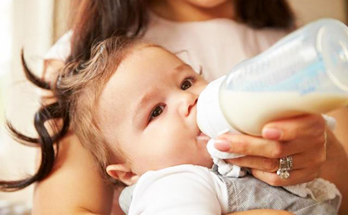 Маленькая кареглазка пьёт молочную смесь из бутылочки