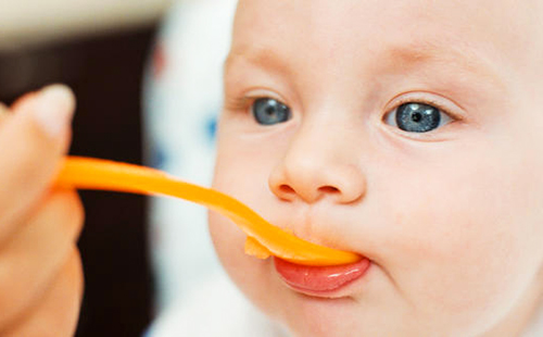 Малыш с удовольствием потребляет витаминчики с апельсиново-оранжевой ложки