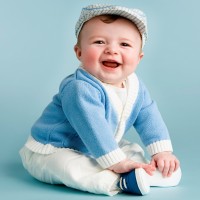 Малыш в кепке сидит и улыбается
