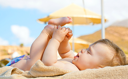 Счастливый младенец под ласковым солнышком на пляже