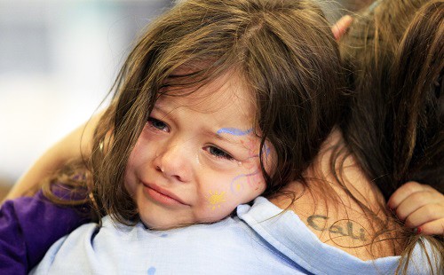 Девочка плачет на плече у мамы после трудного дня