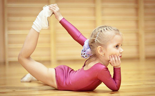 Маленькая гимнастка небрежно лежит в замысловатой позе