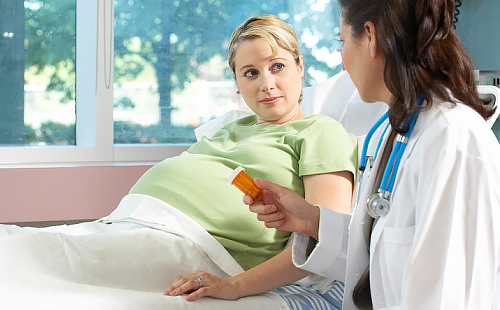 Беременная близнецами женщина внимательно слушает врача