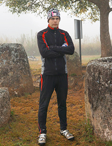 Инструктор в чёрном тренировочном костюме стоит среди больших камней