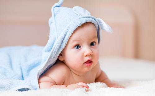 Младенец с голубым полотенцем на голове