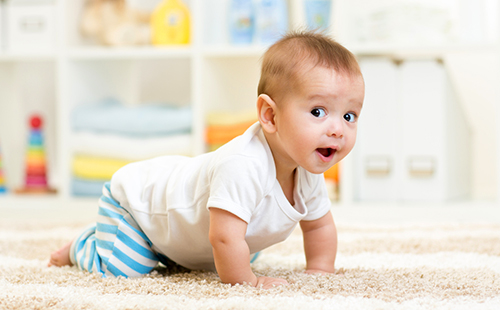 Весёлый малыш ползёт по светлому ковру