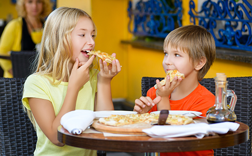 Мальчик и девочка едят пицу