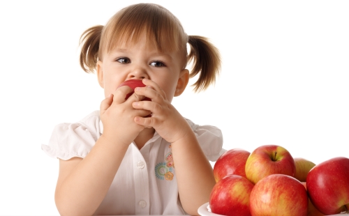 Девочка с хвостиками ест яблоко