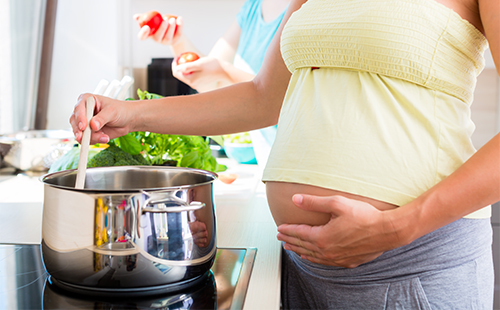 Беременная женщина варит суп