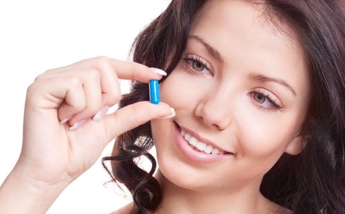 Женщина держит синюю таблетку в руке