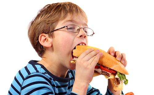 Мальчик ест гамбургер