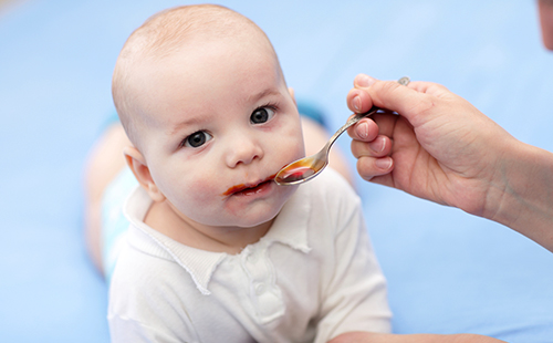 Младенец пьёт сироп с ложечки