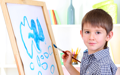 Мальчик рисует на мольберте